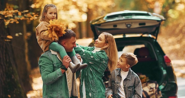 Familie mit dem Auto im Herbst, die Blätter der Bäume sind gelb